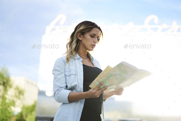 , charming hipster girl checking location tracking orientation for walking around city during sunny