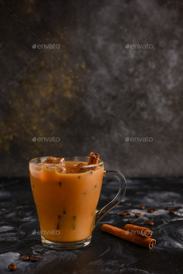  Iced coffee with milk on a dark background with Cinnamon stick and ice cubes.