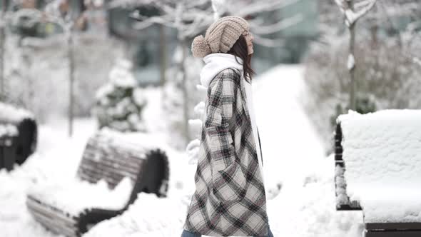 A Happy Young Darkhaired Woman in Round Glasses and a Plaid Coat Walks Outside in the Afternoon on a alt