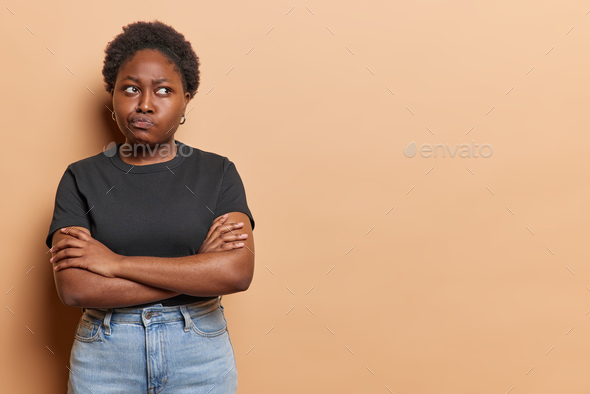 Horizontal Shot Of Dark Skinned Plump Woman Keeps Arms Folded Purses Lips Feels Discontent 0030