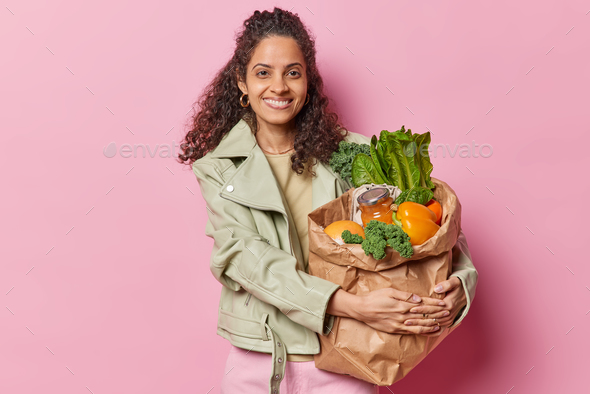 Photo of cheerful woman holding shopping bag full of groceries paper package with products returns