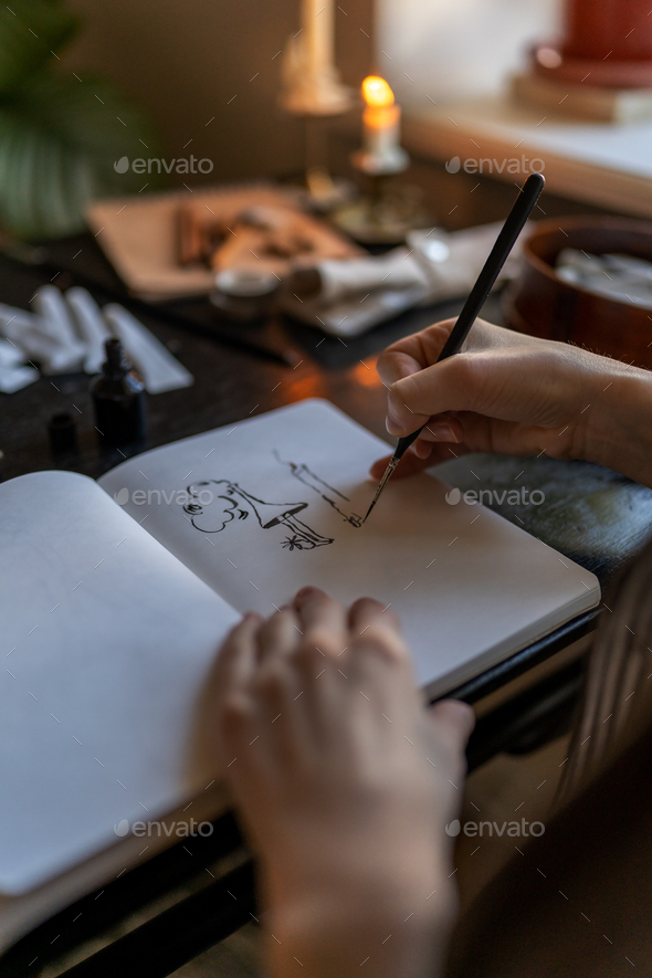 Artist holding fountain pen drawing with ink, creating artwork Stock