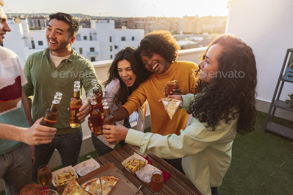 group of diverse friends partying on rooftop drinking alcohol and ...