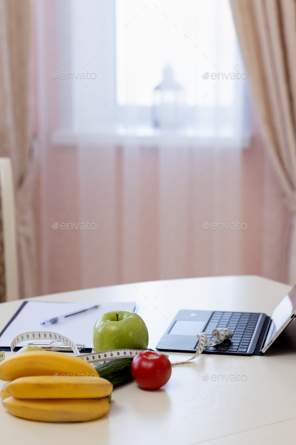 Bananas, apple, vegetable, laptop, tape-measure, tablet, on dietitian's table to calculate ration - Stock Photo - Images