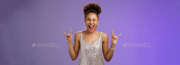 Excited good-looking african-american woman in glittering silver shiny dress having fun amusing