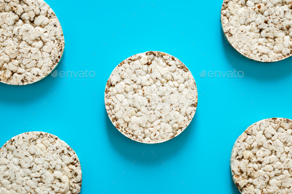 Puffed rice cakes on blue background, flat lay.