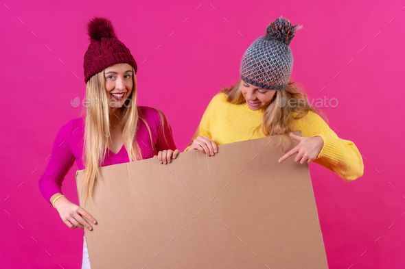 Females with hats and colorful blouses holding empty cardboard for