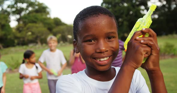 Portrait of smiling boy playing with water gun alt
