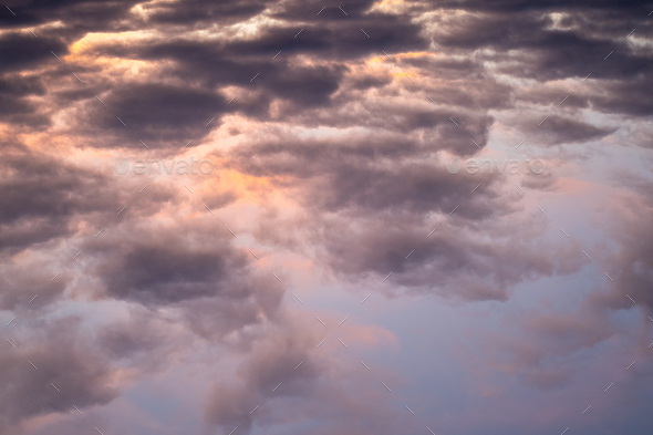 Landscape photo of big, pink cumulonimbus clouds in a stormy sky at sunset. Moody sunset sky.