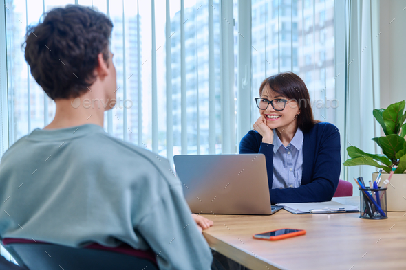 School psychologist supporting guy student, sitting in office of educational building