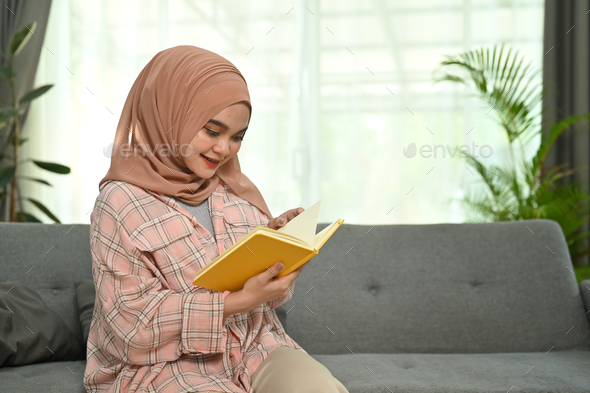 Happy young muslim woman wear hijab and casual clothes reading