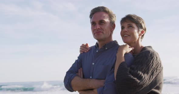 Caucasian couple enjoying free time by sea on sunny day embracing and kissing alt