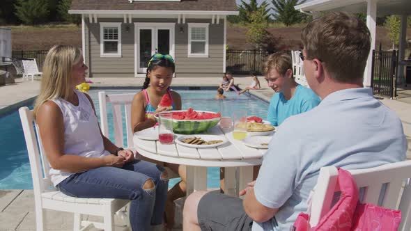 Family having lunch by backyard pool