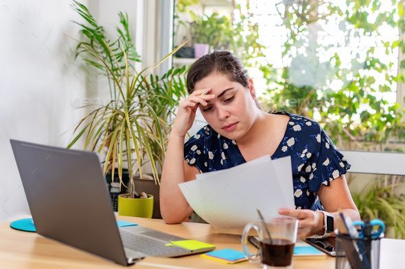 a woman looking at paperwork at the office, stressed