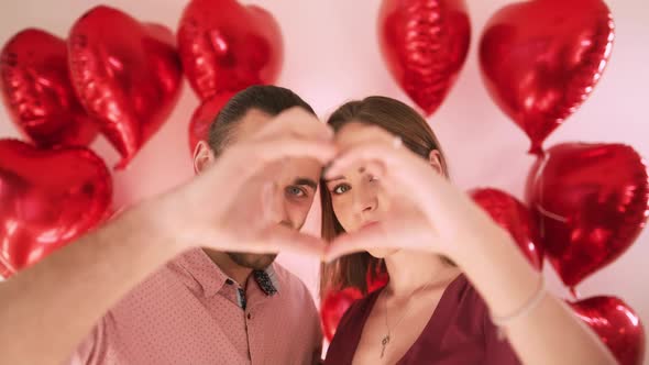 Happy Beautiful Young Woman and Handsome Man Making Heart Shape Hand Gesture alt