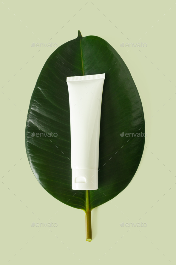 White plastic tube mockup for cream, moisturizer, lotion, facial cleanser or shampoo on leaf