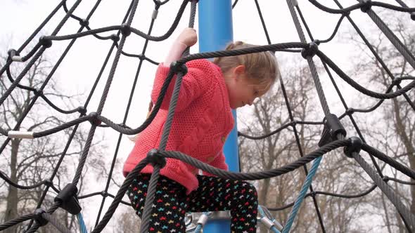 Concentrated Kid with Plait Stands on Large Rope Attraction alt