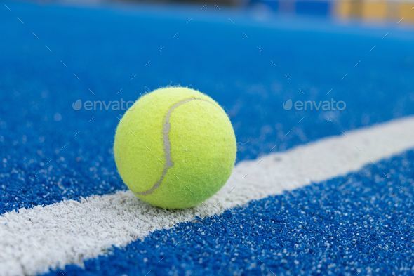 a tennis ball on the side of a court with lines in the middle