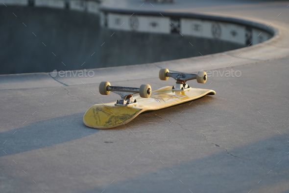 Yellow skateboard lying upside down on a skate track