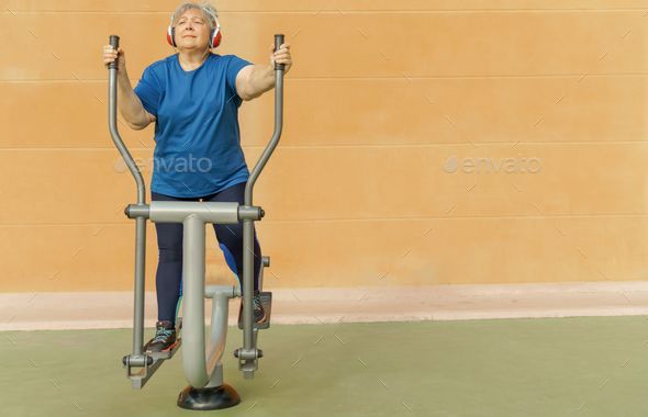 active elderly woman training on a machine in the park Stock Photo