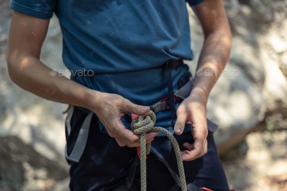 Man adjusting the rope tied around his waist Stock Photo by wirestock