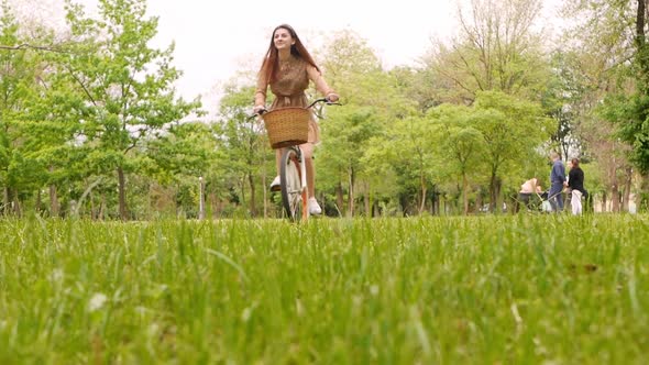 A Young Woman Rides Her Bike on the Grass