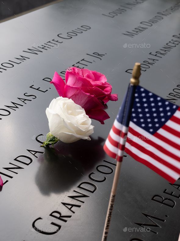 Vertical closeup shot of an American flag and roses on a gravestone