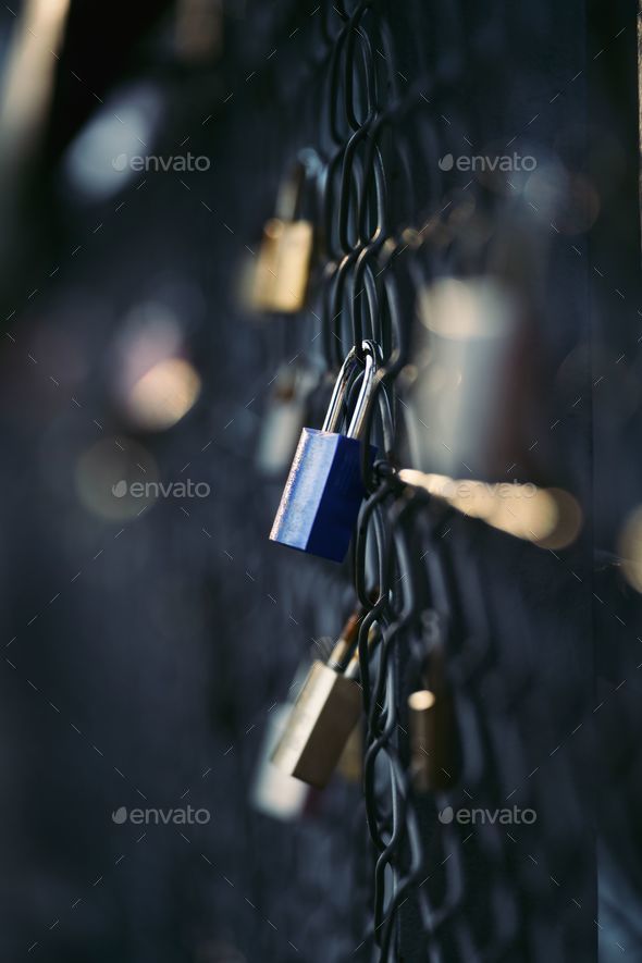 Close-up shot of a padlock on an ornamental metal fence, fastened to the links of the chain