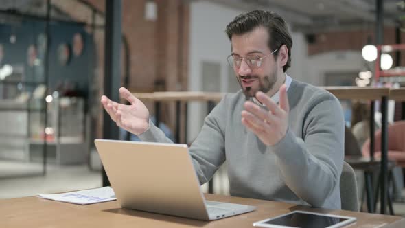 Young Man Talking on Video Call on Laptop in Office alt