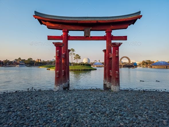a red tori tori gate in front of a lake and the city skyline