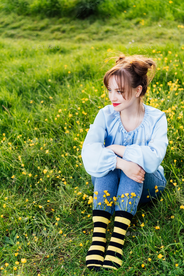 Young woman wearing blue blouse, jeans and striped black and yellow socks with flowers inside