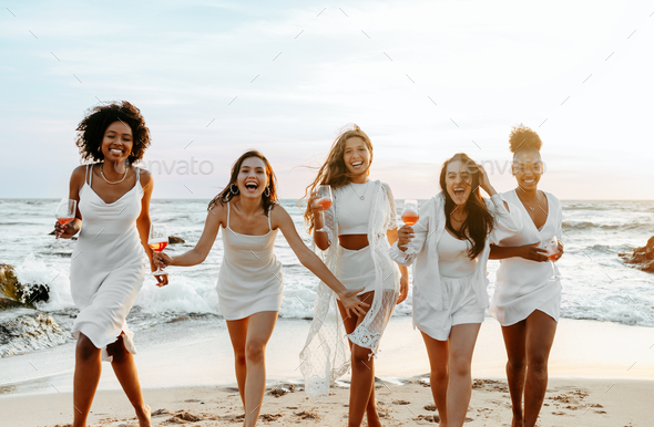 Bride's team. Group of happy ladies dancing and having fun on the beach, having hen party at