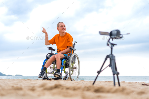 Portrait of a disabled person in a wheelchair recording a video clip next to the beach