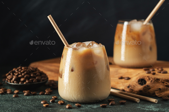 Ice coffee in a glass with cream poured over and coffee beans