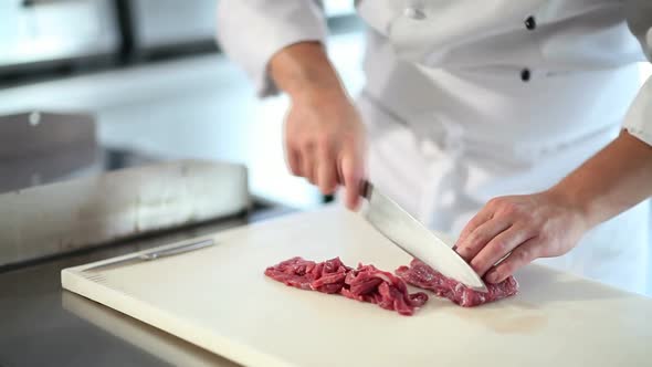 chef cook hands cut the meat on chopping board in restaurant kitchen close up