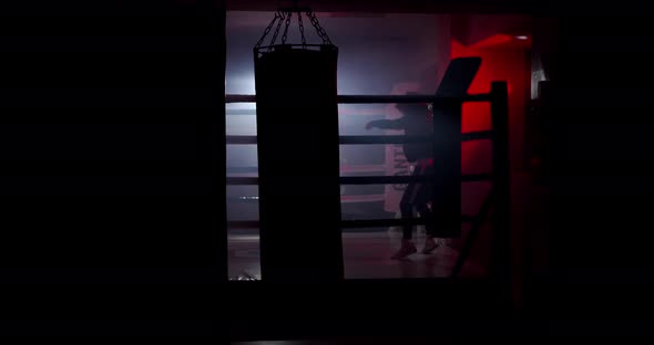A boxer boxing with a shadow draws quick punches in a semi-dark ring with a backlight alt