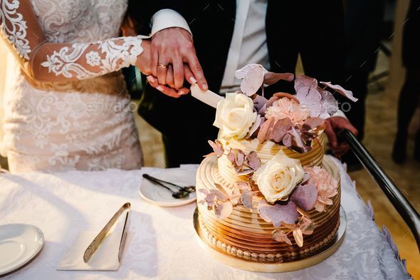 Bride and a groom is cutting their rustic wedding cake on wedding banquet.  Hands cut the Stock Photo by kurinchukolha