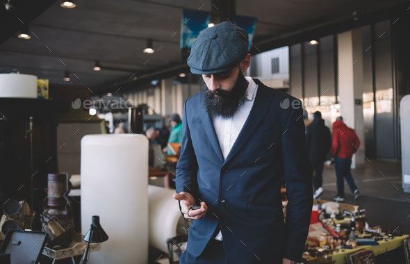 Concentrated stylish bearded man visiting flea market