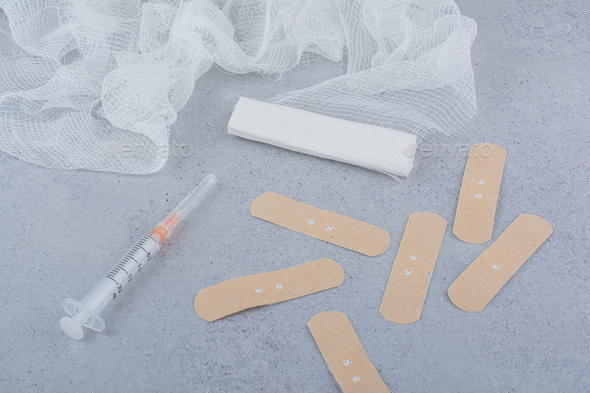 Band aid plaster strips, bandage and syringe on marble surface