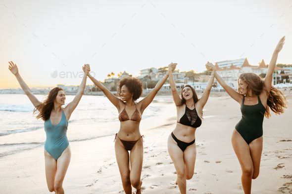 Four girlfriends in swimwear enjoying beach day, female friends having fun  during their summer Stock Photo by Prostock-studio