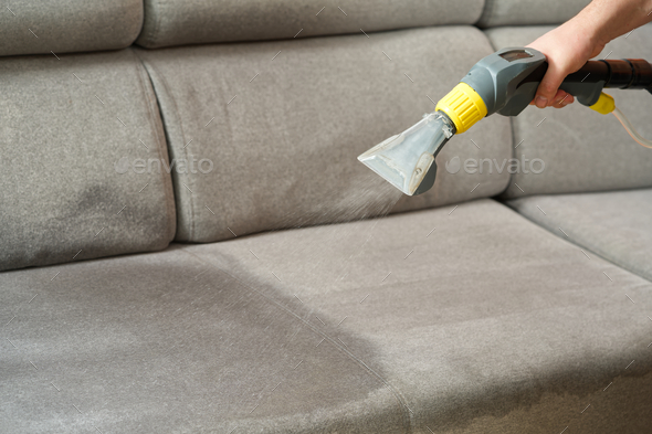 Male Worker Cleaning Sofa With Vacuum Cleaner Stock Photo