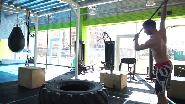 A Man Hits a Hammer on a Large Tire in the Gym alt