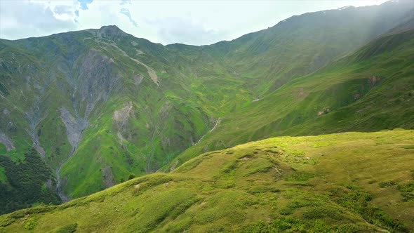 Aerial drone view of nature in Georgia. Caucasus Mountains, greenery, valleys, lush clouds, shack on alt