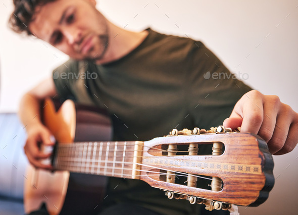 Closeup, man and tuning guitar for music, talent and creative skill of sound production in home stu