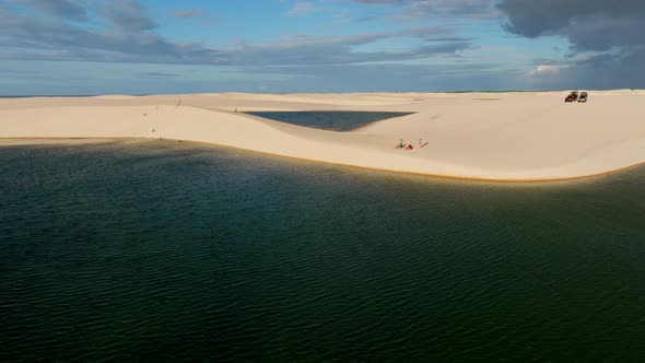 H264drone Passes Over A Large Blue Lagoon, With Dunes In The Background