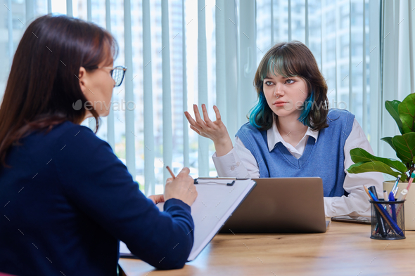 School psychologist supporting girl student, sitting in office of educational building