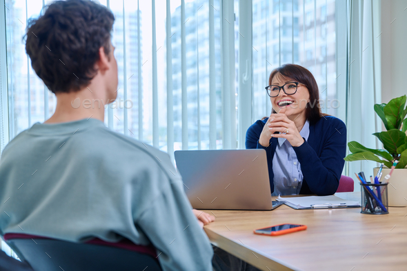 School psychologist supporting guy student, sitting in office of educational building