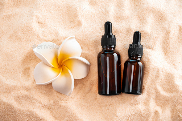 Top view essential oils and plumeria flower on a sandy beach. Stock Photo  by aleeenot