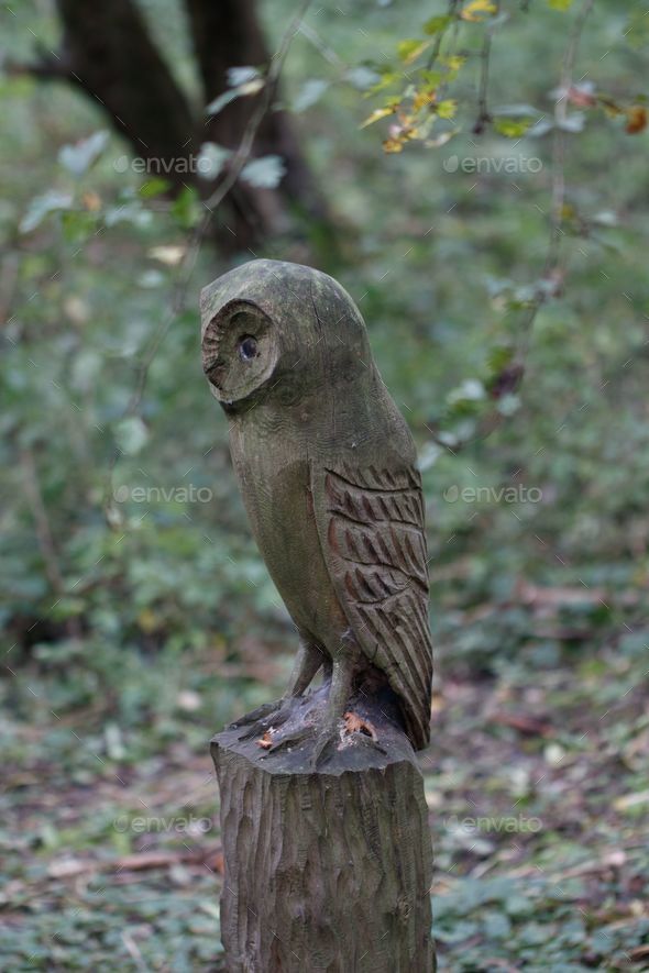 Small owl statue perched atop a tree stump