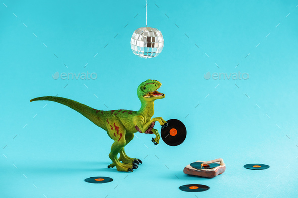 Cute green dinosaur toy holding a vinyl record and listen vinyl on vinyl record player